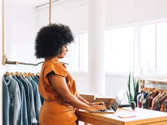 Female business owner using a laptop in her clothing store