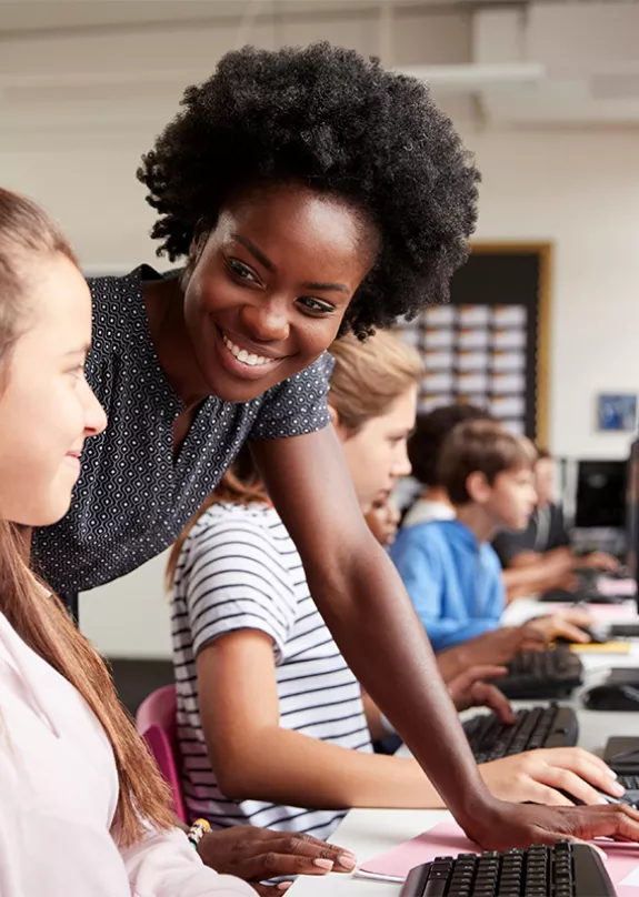 Image of a teacher with a student who is on a computer at school. 